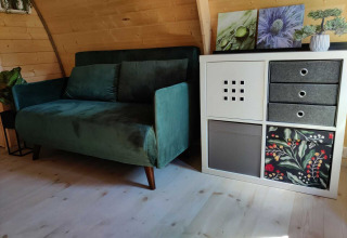 Billede af en grøn sofa og en moderne hvid reol i en træhytte ved Woodlodge, Wilsumer Berge, Tyskland.