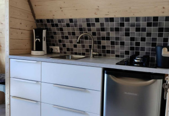 Kitchenette moderne avec placards blancs et carrelage mosaïque à la Woodlodge, Wilsumer Berge, Allemagne.