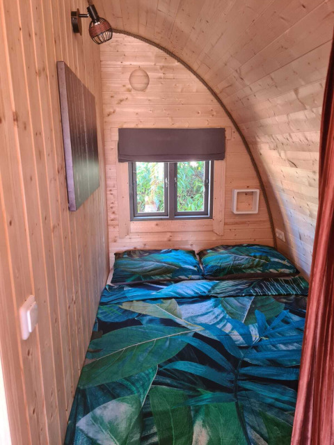 Træbeklædt soveområde i Woodlodge på Wilsumer Berge, Tyskland, med dobbeltseng og store vinduer.