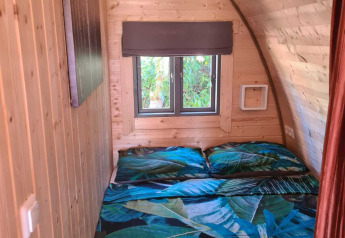 Træbeklædt soveområde i Woodlodge på Wilsumer Berge, Tyskland, med dobbeltseng og store vinduer.