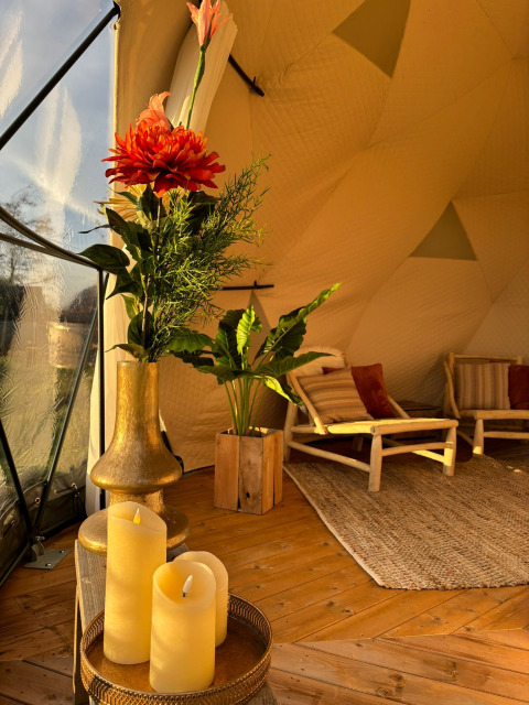 Decoración acogedora en Cast Away Dome con flores, velas y sillas de madera en TinyParks Cast Away, Países Bajos.