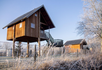 Boomhut bij Holiday Park Mölke, Nederland, op een ijzige ochtend met een heldere blauwe lucht.