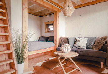 Gemütliches Baumhaus mit modernem Interieur, Sofa, Bett und Holztisch im Holiday Park Mölke, Niederlande.