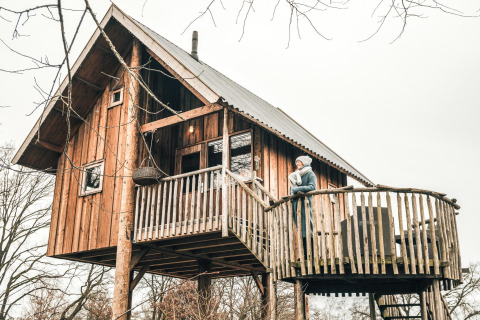 Cabane dans les arbres au Holiday Park Mölke aux Pays-Bas, une personne profite du balcon.