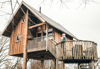 Casa sull’albero al Holiday Park Mölke nei Paesi Bassi con una persona sul balcone panoramico.