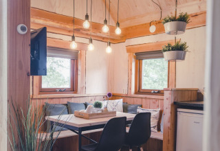 Inviting tree house interior with dining space, hanging plants, and cozy windows at Holiday Park Mölke.