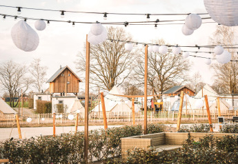 Boomhut en tenten op Holiday Park Mölke in Nederland, versierd met lichtslingers en lantaarns.