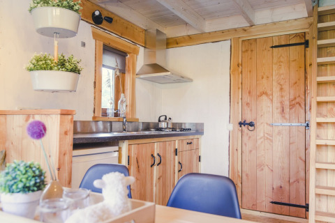 Acogedora cocina en una casa del árbol en Holiday Park Mölke, Países Bajos, con interiores de madera.