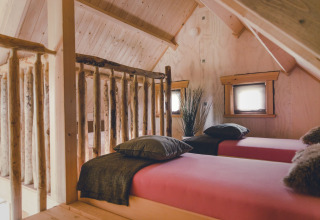 Knusse boomhut slaapkamer met twee eenpersoonsbedden en houten wanden bij Holiday Park Mölke, Nederland.
