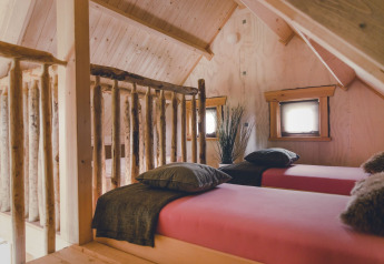 Gezellige boomhutkamer met twee eenpersoonsbedden en houten wanden bij Holiday Park Mölke, Nederland.