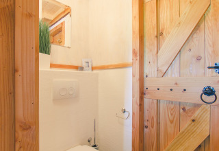 Bagno luminoso in legno con toilette moderna in una casa sull’albero a Holiday Park Mölke, Paesi Bassi.