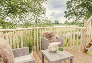 Tree house terrace at Holiday Park Mölke, Netherlands, with seating and a rustic view over the countryside.