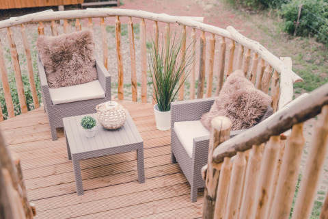 Balcón de casa del árbol con dos sillones, mesa y plantas en Holiday Park Mölke, Países Bajos.