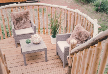 Balcón de casa del árbol con dos sillones, mesa y plantas en Holiday Park Mölke, Países Bajos.