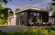 Modern river lodge at Holiday Park Mölke in the Netherlands, featuring a spacious patio and lounge chairs.