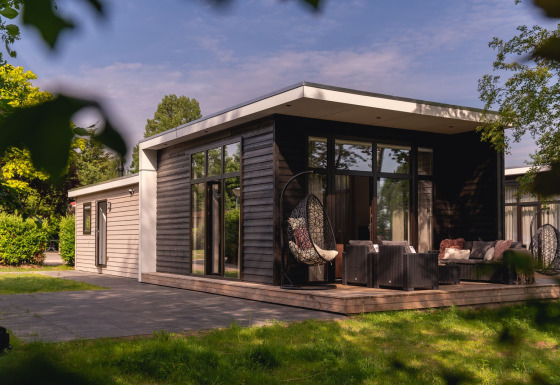 Moderne rivierhut met groot terras en loungezetels bij Holiday Park Mölke in Nederland.