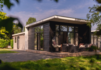 Moderne hytte ved floden med stort terrasseområde og loungemøbler i Holiday Park Mölke, Holland.