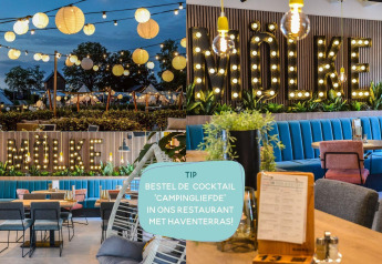 Glampingterrein met lampionnen en restaurant met blauwe banken en grote verlichte letters 'Mölke'.