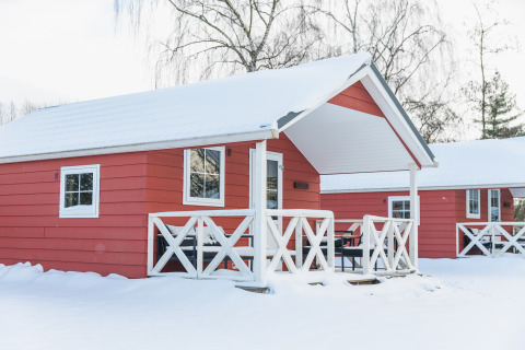 Cabañas rojas de estilo escandinavo con nieve en los techos en Holiday Park Mölke, Países Bajos.