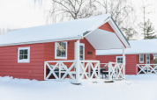 Red Scandinavian lodge cabins with snowy roofs and porch at Holiday Park Mölke in the Netherlands.