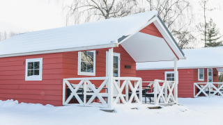 Rode Scandinavische lodges met besneeuwd dak bij Holiday Park Mölke in Nederland tijdens de winter.