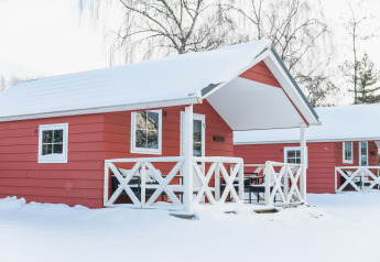Rode Scandinavische lodges met besneeuwd dak bij Holiday Park Mölke in Nederland tijdens de winter.
