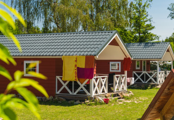 Røde skandinaviske hytter med hvide verandaer ved Holiday Park Mölke i Holland, solrig sommerdag.