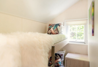 Lichte gezellige kamer met hoogslaper en venster in een Scandinavische lodge bij Holiday Park Mölke, Nederland.
