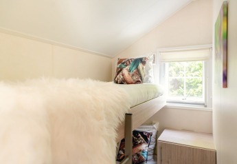 Bright cozy room with lofted bed and window at Scandinavian lodge in Holiday Park Mölke, Netherlands.