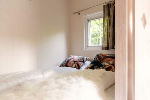 Dormitorio acogedor con almohadas coloridas y manta peluda en una cabaña escandinava en Holiday Park Mölke, Países Bajos.