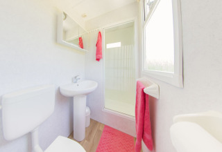 Baño luminoso y moderno en la Scandinavian lodge de Holiday Park Mölke, Países Bajos, con detalles rosados.