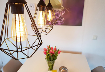 Moderne skandinavische Hängelampen und Tulpenvase auf einem Tisch in der Scandinavian Lodge im Holiday Park Mölke, Niederlande.