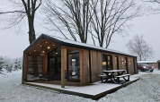 Casa de madera en Wilsumer Berge, Alemania, rodeada de nieve y árboles desnudos en un entorno invernal.