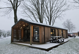 Casa de madera en Wilsumer Berge, Alemania, rodeada de nieve y árboles desnudos en un entorno invernal.