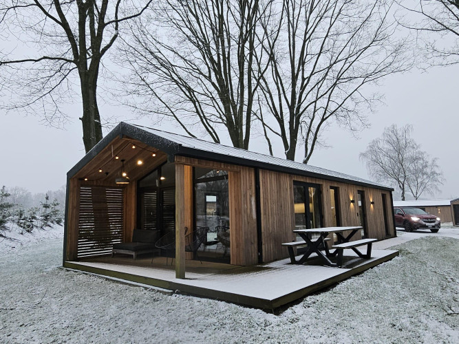Casa de madera en Wilsumer Berge, Alemania, rodeada de nieve y árboles desnudos en un entorno invernal.