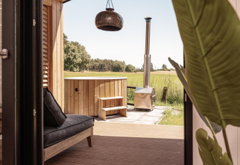 Vista desde una cabaña en Wilsumer Berge, Alemania, con terraza privada, sofá y bañera de hidromasaje exterior.