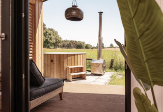 Vista desde una cabaña en Wilsumer Berge, Alemania, con terraza privada, sofá y bañera de hidromasaje exterior.