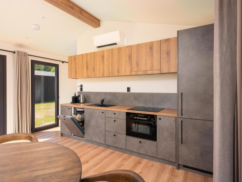 Cuisine de lodge moderne avec armoires en bois, éléments gris, lave-vaisselle ouvert et table à manger devant.