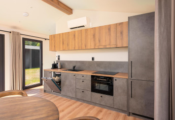 Cucina moderna in lodge con mobili in legno, dettagli grigi, lavastoviglie aperta e tavolo da pranzo davanti.