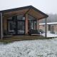 Moderne Holzlodge mit Glasfront bei Wilsumer Berge in Deutschland, winterlich und leicht verschneit.