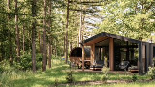 Natuurlodge met panoramische sauna in het bos bij Wilsumer Berge, Duitsland, omringd door hoge bomen.