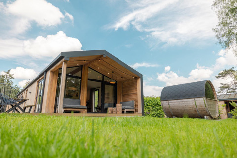 Nature Lodge con sauna panorámica, cabaña moderna de madera sobre césped verde en Wilsumer Berge, Alemania.