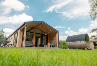 Natur Lodge med panorama sauna, moderne træhus på grøn græsplæne under blå himmel i Wilsumer Berge, Tyskland.