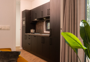 Moderne lodge-keuken met donkere kasten, gaskookplaat, raam, grote gordijnen en woonkamerstuk.