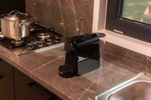 Cocina moderna de lodge con cafetera, estufa de gas con olla y fregadero al lado de la ventana.