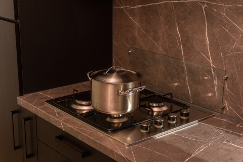 Foto de cocina con una olla de acero inoxidable con tapa sobre una estufa de gas en una encimera de mármol en una cabaña.