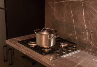 Foto de cocina con una olla de acero inoxidable con tapa sobre una estufa de gas en una encimera de mármol en una cabaña.