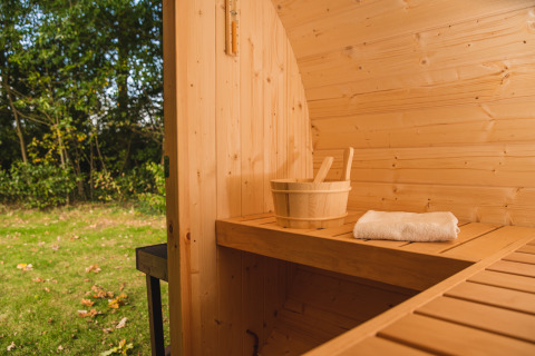 Panca in sauna di legno al Luxury Lodge di Vakantiepark Hölte, Paesi Bassi, con secchio e asciugamano.