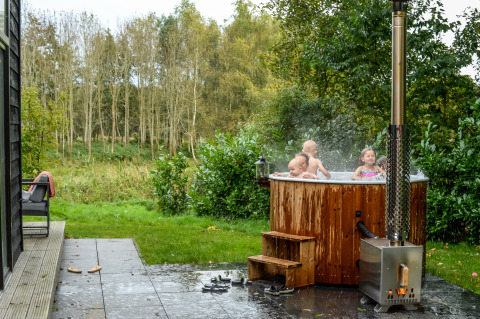 Kinder entspannen sich im Whirlpool an einer kleinen Hütte im Ferienpark Mölke, Niederlande.