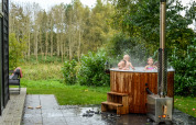 Children enjoy a hot tub beside the River Cabin tiny house at Holiday Park Mölke, Netherlands.